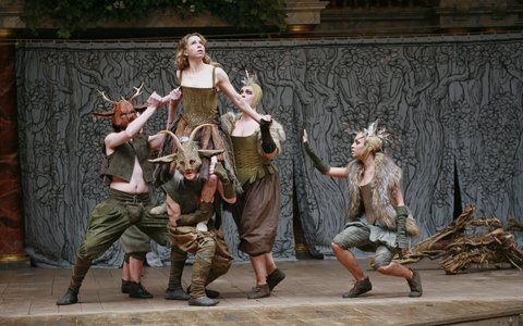 Michelle Terry as Titania being held in the by three actors wearing woodland masks